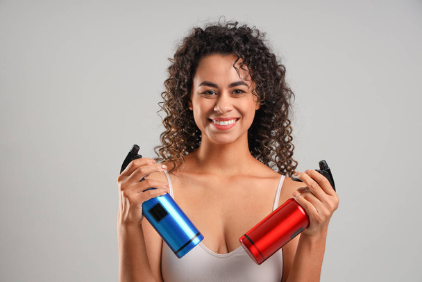 Beautiful African-American woman with hair sprays on light background - Photo, Image