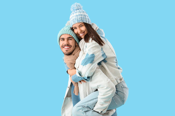 Pareja cariñosa en ropa de invierno sobre fondo azul - Foto, Imagen