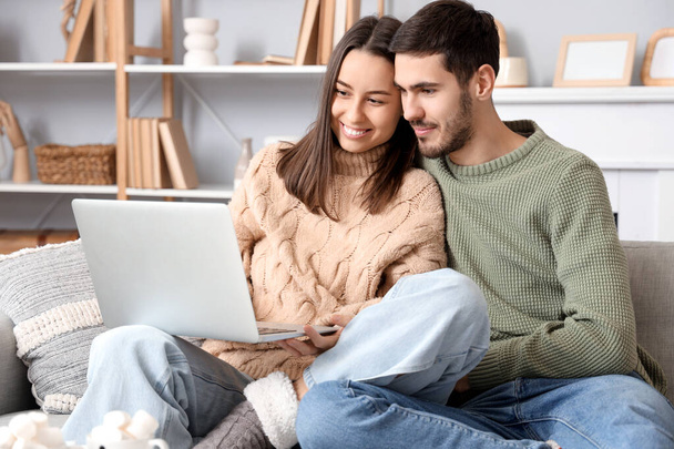 Loving couple using laptop at home on winter day - Photo, Image