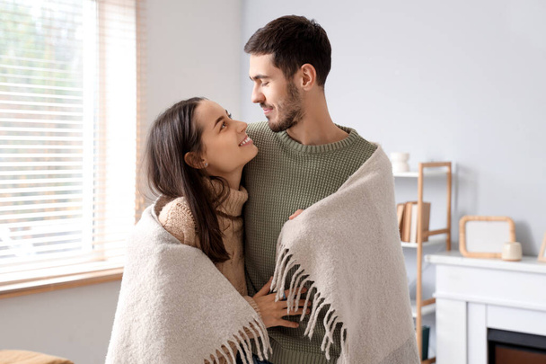 Loving couple with warm plaid at home on winter day - Photo, Image