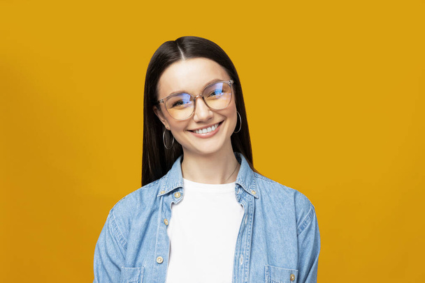 Une belle fille en lunettes pose sur un fond jaune - Photo, image
