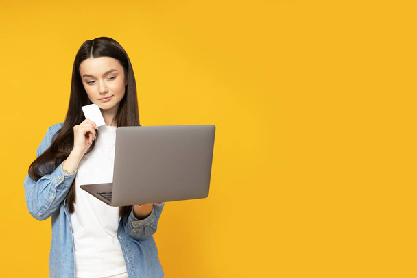 Aranyos fiatal nő laptoppal és hitelkártyával a kezében - Fotó, kép