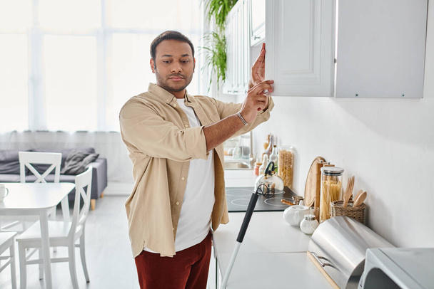 attractive indian disabled man in casual attire with walking stick reaching products on kitchen - Photo, Image