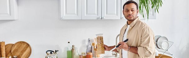 komea intialainen mies sokeus rento asu poiminta purkki makaroni kun keittiö, banneri - Valokuva, kuva