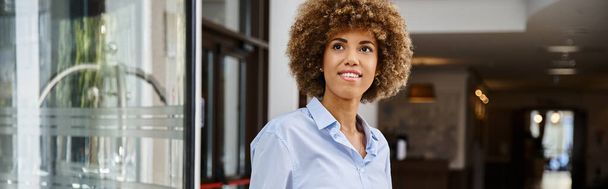 Розумно одягнена і щаслива афроамериканка з кучерявим волоссям, що стоїть у готельному лобі, банер - Фото, зображення