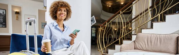 sztandar szczęśliwej Afroamerykanki z kawą na wynos i smartfonem siedzącym w hotelowym lobby - Zdjęcie, obraz