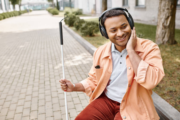 Neşeli sakat Hintli adam kulaklık takıyor ve müzik dinliyor. - Fotoğraf, Görsel
