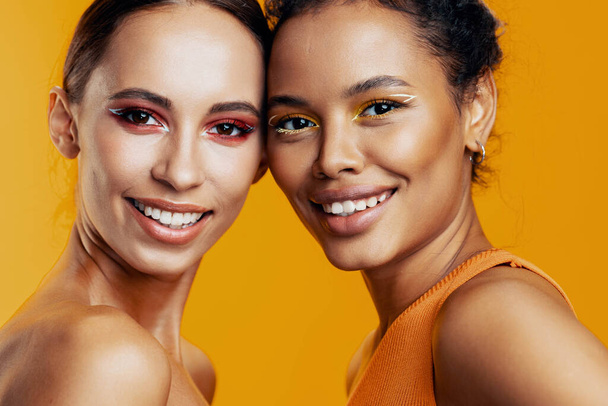 Γυναίκα κίτρινο στούντιο make-up αγώνα bodycare ευτυχισμένη λάμψη αναμιγνύεται μαζί αμερικανικό όμορφο μοντέλο δύο πολύχρωμα ελκυστική πορτρέτο του δέρματος της Αφρικής ομορφιά πρόσωπο - Φωτογραφία, εικόνα