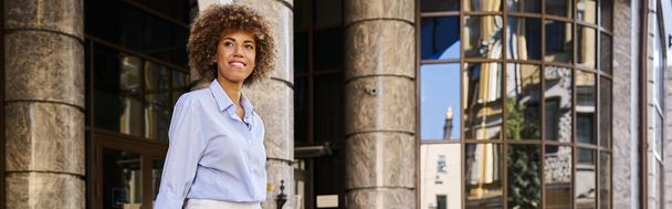 heureuse femme afro-américaine souriante et debout devant l'hôtel, bannière horizontale - Photo, image