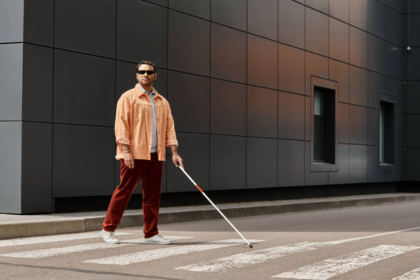 atraente indiana deficiente homem em jaqueta laranja com óculos e vara com parede cinza no fundo - Foto, Imagem