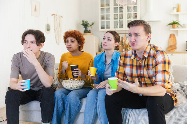 Eine Gruppe von Freunden schaut sich zu Hause Fußballspiele im Fernsehen an. Die Fußballfans enttäuschten mit einem torlosen Spiel. Freundschaft, Sport und Unterhaltung. Kumpels schauen gemeinsam Meisterschaft - Foto, Bild