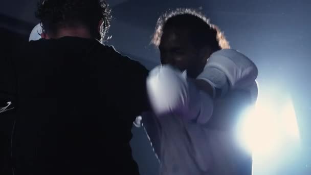 Бой колено бьет противника внутри боксерского ринга с драматической подсветкой. Два боксера в напряженной конфронтации, пинают соперника - Кадры, видео