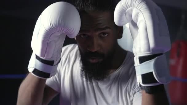 Bojovník mlátí a kopá do kamery, bojuje uvnitř boxerského ringu, jeden mladý černoch kopne do kolena - Záběry, video