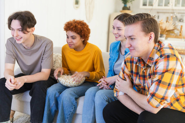 Group of friends watching sport match soccer football game on tv. Happy football fans celebrating victory at home. Friendship sports entertainment concept. Diverse buddies having fun together at home - Photo, Image