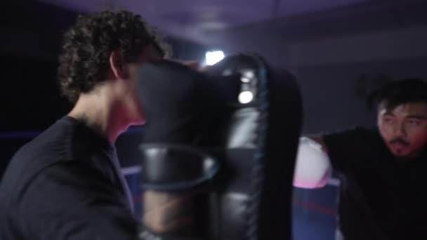 Escena de anillo de boxeo de Muay Thai Sportsman perforando y pateando almohadillas con iluminación dramática - Imágenes, Vídeo