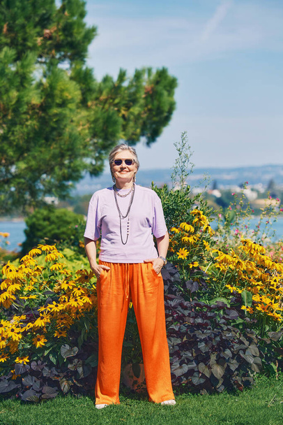 Открытый портрет счастливой пожилой женщины, наслаждающейся прекрасным днем в летнем парке - Фото, изображение
