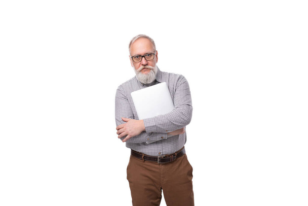 Un homme d'affaires âgé de 60 ans avec une moustache et une barbe grise vêtu d'une chemise et d'un pantalon travaille dans le domaine de l'informatique. - Photo, image