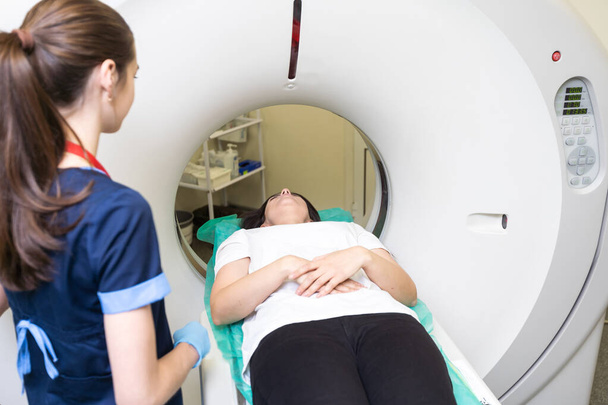 Jolie jeune femme qui passe un examen de tomodensitométrie axiale informatisée au scanner CAT dans un hôpital moderne. - Photo, image