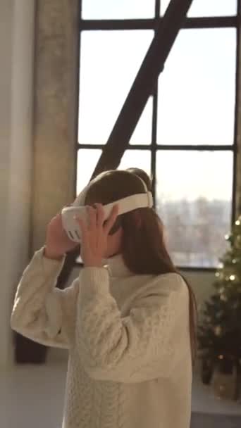 Uma jovem bonita está examinando uma árvore de Natal enquanto usa óculos de realidade virtual. Imagens 4k de alta qualidade - Filmagem, Vídeo