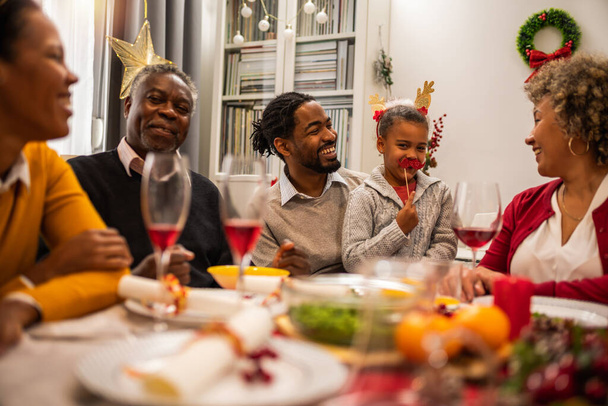 Familia divirtiéndose en Nochebuena junto a la mesa. - Foto, Imagen