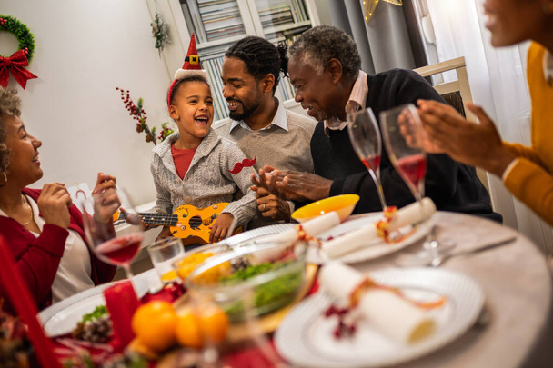 Familia divirtiéndose en Nochebuena junto a la mesa. - Foto, imagen