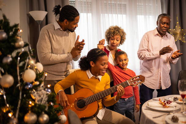 Afroamerikanische Familie spielt an Heiligabend Gitarre und singt. - Foto, Bild