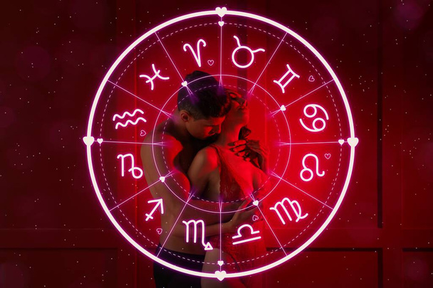 Intohimoinen nuori pari ja Zodiac pyörä punaisella taustalla. Seksuaalinen yhteensopivuus horoskooppi - Valokuva, kuva