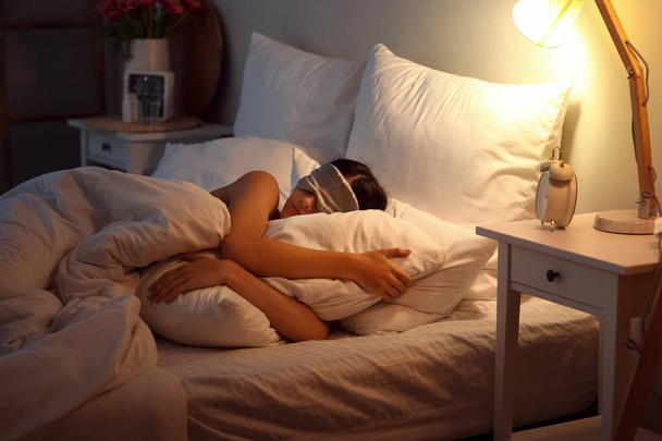 Nuori nainen maski nukkuu sängyssä yöllä - Valokuva, kuva