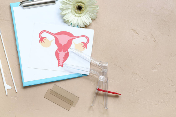 Jinekolojik spekulum, kadın rahminin çizimi, pano ve bej arkaplan üzerindeki pap smear test araçları - Fotoğraf, Görsel