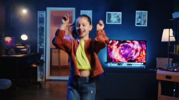 Happy young kid doing viral dance choreography, creating content to generate views and engagement. Cute girl having fun dancing around living room, entertaining audiences - Footage, Video