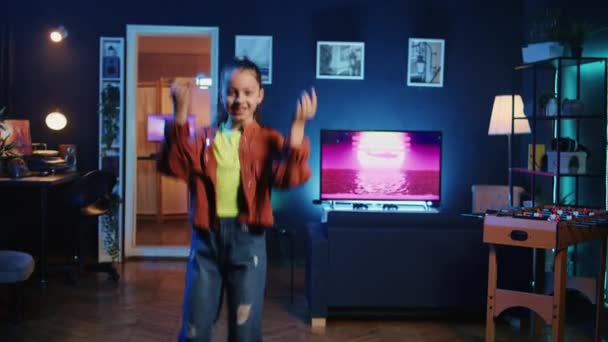 Nahaufnahme eines fröhlichen Kindes, das seine Anhänger im neonbeleuchteten Heimstudio mit unglaublichen Tanzschritten verzaubert. Internet-Star zu Hause zeigt coole Tanzkünste und filmt familienfreundliche Inhalte - Filmmaterial, Video