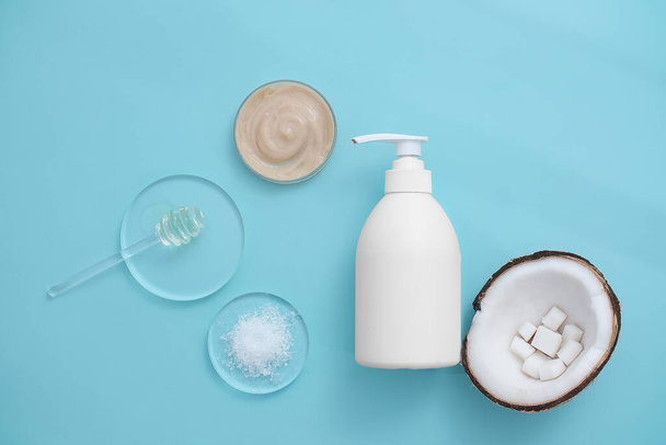 Płytka Petriego zawierająca jasnobrązowy żel pod prysznic z ekstraktem kokosowym, nieoznakowaną białą butelkę kosmetyczną i świeży kokos. Żel pod prysznic kokosowy ma słaby, przyjemny zapach. - Zdjęcie, obraz