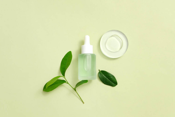 Organic serum with fresh green tea leaves, liquid drops displayed on a transparent platform, pastel background. Minimalist concept with beauty products. - Photo, Image