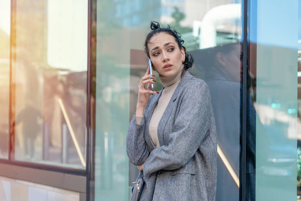 δυστυχισμένη γυναίκα ή φοιτήτρια με μπουφάν και τζιν διασχίζουν το δρόμο και μιλάνε στο τηλέφωνο - Φωτογραφία, εικόνα