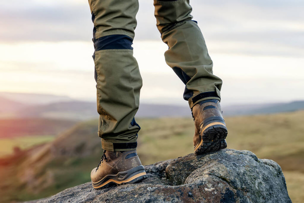 homem de botas speshial andando nas montanhas chegando ao destino e no topo da montanha em Peak District ao pôr do sol no dia de outono Travel Lifestyle conceito - Foto, Imagem