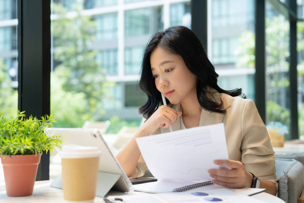 Attraktive asiatische Geschäftsfrau sitzt am Laptop und bereitet Bericht auf weißem Tisch vor. - Foto, Bild