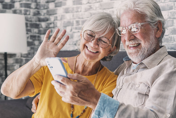 Joyeux couple de retraités utilisant le téléphone mobile pour un appel vidéo ensemble, parler aux relations, avoir de bonnes nouvelles, s'amuser, sourire et rire. Insouciants retraités matures bavarder en ligne sur la cellule - Photo, image