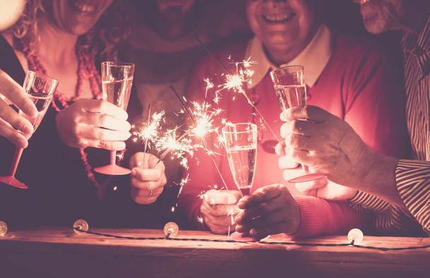 csoport az emberek ünneplik az új évet vagy más party együtt csillagszórók és pezsgő - család idősek és felnőttek élvezik - Fotó, kép