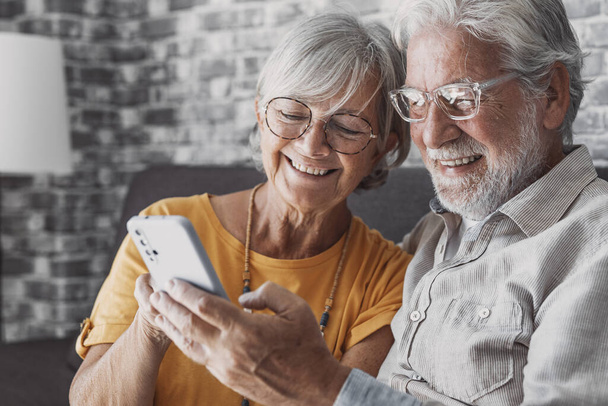 Elderly grandfather and grandmother spend time having fun using smartphone apps, middle-aged wife enjoy online entertainments, taking selfie with old husband, older generation and modern tech concept - Photo, Image