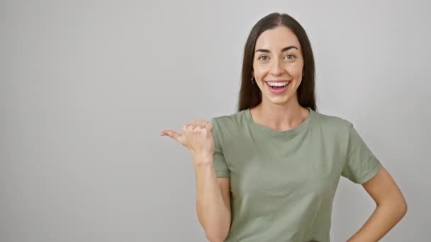 Joyful young hispanic woman, beautifully dressed in casual clothes, showing a big thumbs up, while smiling widely and pointing to the side on isolated white background. - Footage, Video