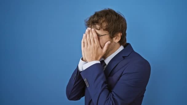 Een gestresste, jonge Spaanse man in een blauw zakenpak, huilt. depressie expressie zichtbaar op geïsoleerde achtergrond - Video