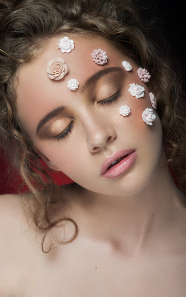 Romantic nude young beautiful girl with white flowers on her face and soft curls on dark background. - Foto, imagen