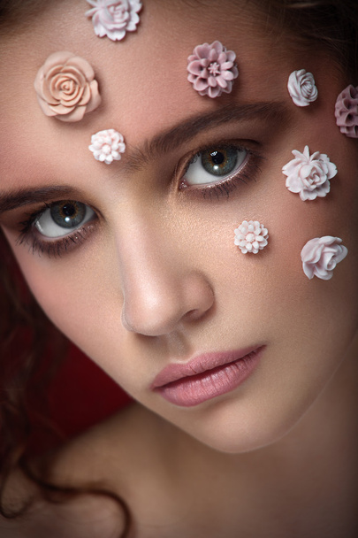 Romantic nude young beautiful girl with white flowers on her face and soft curls on dark background. - Foto, Bild