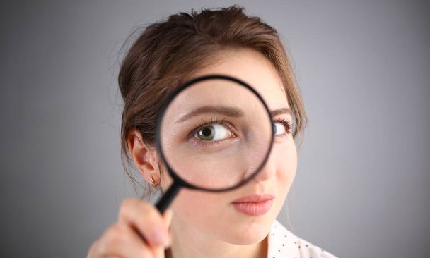 Inquisitive young woman looking through magnifying glass. Search for business ideas and new creative creative information - Photo, Image