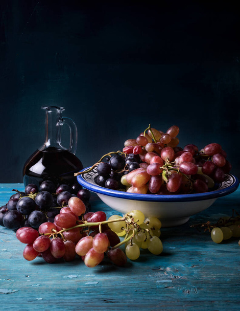 Бутылка красного вина с виноградом на старом деревянном фоне.  - Фото, изображение