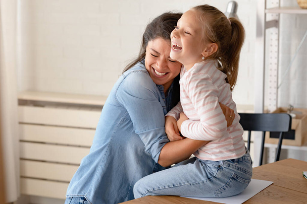 Ein freudiger und liebevoller Moment entfaltet sich, als eine fröhliche Mutter und ihre Tochter ein warmes Lächeln teilen, kuscheln und gemeinsam Spaß haben.. - Foto, Bild