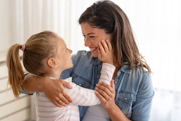 Radosny i czuły moment rozwija się jako radosna matka i jej córka dzielą ciepłe uśmiechy, przytulanie i zabawy razem. - Zdjęcie, obraz