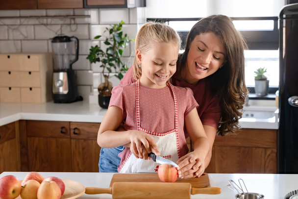Красивая счастливая мать и дочь готовят яблочный пирог на домашней кухне. Осенние развлечения в семье - Фото, изображение