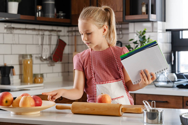 Portret uroczej dziewczynki w domowej kuchni przed przygotowaniem szarlotki - Zdjęcie, obraz