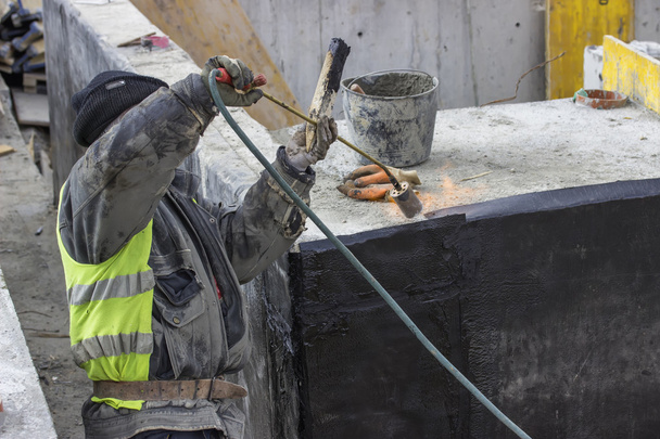Isolierarbeiter lässt Bitumenfilz schmelzen - Foto, Bild